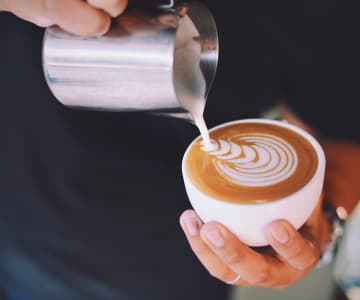 A man pours milk in a coffe